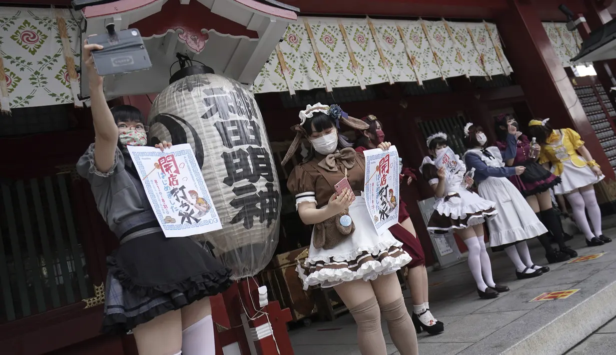 Karyawan mengenakan kostum pelayan dari beberapa kafe bertema pembantu Akihabara berdiri setelah pertemuan doa untuk perlindungan dari COVID-19 dan untuk bisnis yang berkembang di kuil Kanda Myojin, Tokyo (25/7/2020). (AP Photo/Eugene Hoshiko)