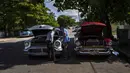 Pengemudi dua mobil antik Amerika memeriksa kendaraannya di Varadero, Kuba, pada Rabu (29/9/2021). Pihak berwenang di Kuba mulai melonggarkan pembatasan COVID-19 di beberapa kota seperti Havana dan Varadero. (AP Photo/Ramon Espinosa)