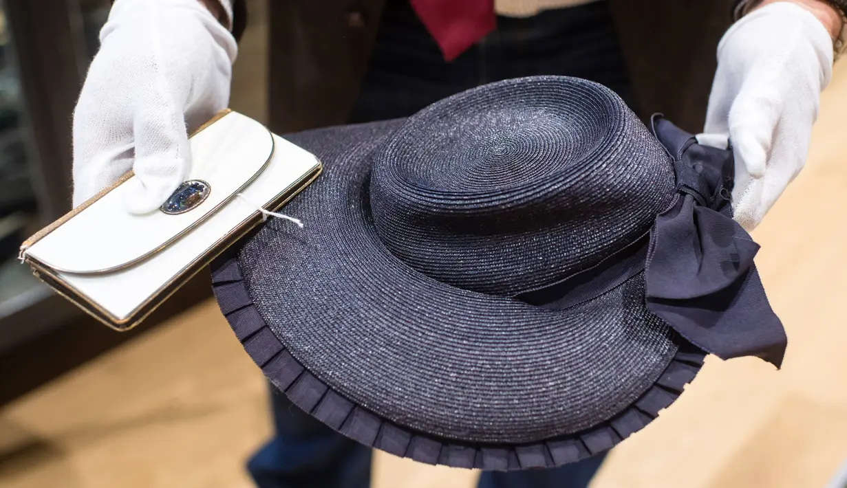Pegawai memegang dompet dan topi jerami milik pasangan Adolf Hitler, Eva Braun sebelum lelang memorabilia Nazi di Grasbrunn, Jerman, Rabu (20/11/2019). Lelang memorabilia Nazi digelar oleh Hermann Historica. (Matthias Balk/dpa via AP)