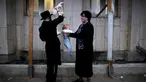 Seorang pria Yahudi Ultra-Ortodoks memegang ayam di atas kepala bayi saat melakukan ritual Kaparot, di Ashdod, Israel, (9/10). Dalam ritual ini ayam putih disembelih sebagai syarat simbolis dari penebusan. (REUTERS/Amir Cohen)