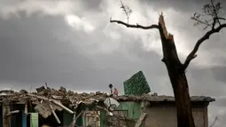 Seorang pria mencari barang miliknya di sebuah bangunan yang hancur dihantam badai tornado di Regla, Kuba (28/1). Hantaman tornado mengakibatkan rumah-rumah hancur berantakan, mobil bergelimpangan hingga pepohonan tumbang. (AP Photo/Ramon Espinosa)