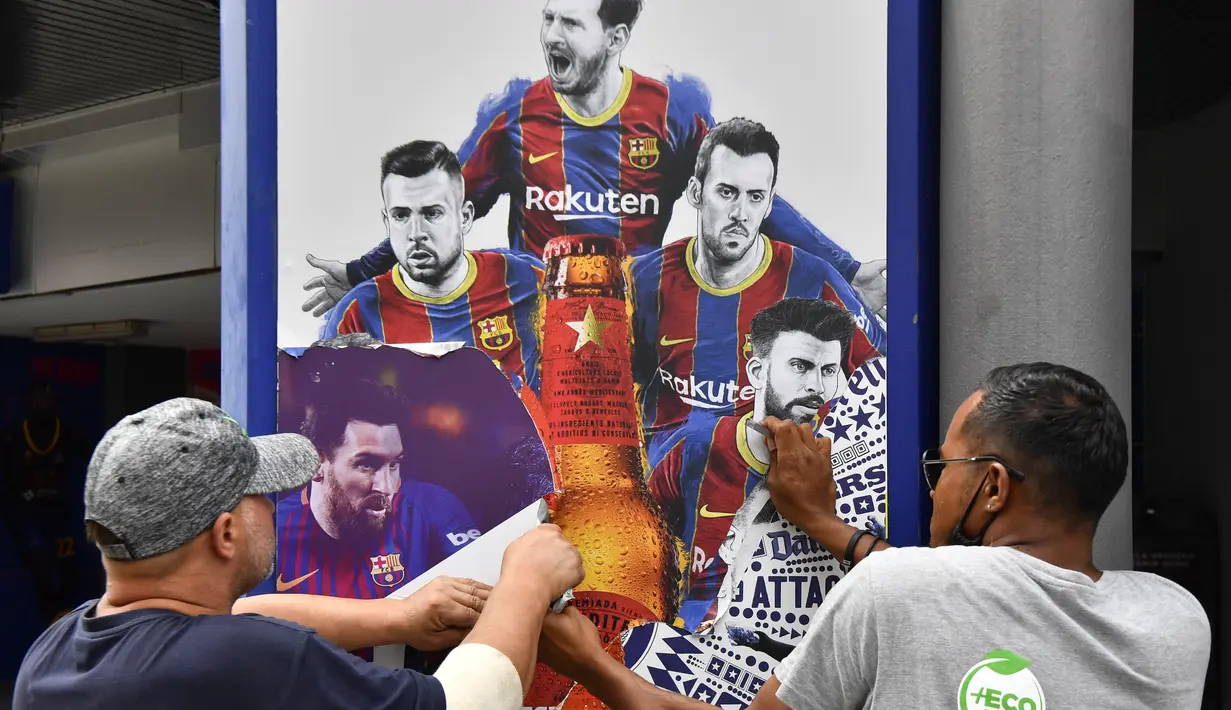 Pekerja melepas poster-poster yang menampilkan pemain depan Barcelona Lionel Messi di stadion Camp Nou di Barcelona (10/8/2021). Prancis menunggu dengan tidak sabar Lionel Messi dengan para pendukung berkumpul di luar lapangan Paris Saint-Germain. (AFP/ Pau Barrena)