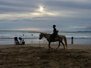 Seorang wisatawan menunggangi kuda saat berlibur Lebaran di Pantai Lhoknga, Aceh Besar, Aceh, Minggu (9/6/2019). (CHAIDEER MAHYUDDIN/AFP)