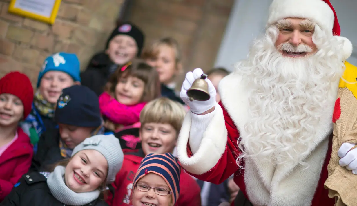 Seorang pria berpakaian Santa Claus berpose dengan anak - anak di kantor pos desa Himmelpfort, Jerman, (10/11/2015).  Sudah anak - anak dari 80 negara mengirim surat kepada Santa Claus. (REUTERS/Hannibal Hanschke)