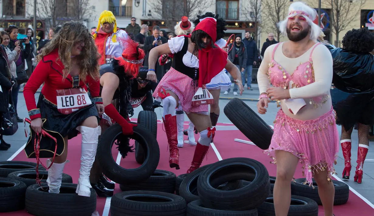 Sejumlah peserta mengenakan kostum dan sepatu hak tinggi mendorong ban saat mengikuti balapan high heels pria di Madrid, Spanyol (18/1). Para pria ini mengenakan sepatu hak tinggi layaknya wanita. (AP Photo / Paul White)