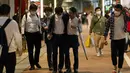Orang-orang berjalan di jalan menuju stasiun kereta api pada malam pertama pencabutan status darurat virus corona oleh pemerintah di Tokyo, Jepang, Jumat (1/10/2021). (AP hoto/Hiro Komae)