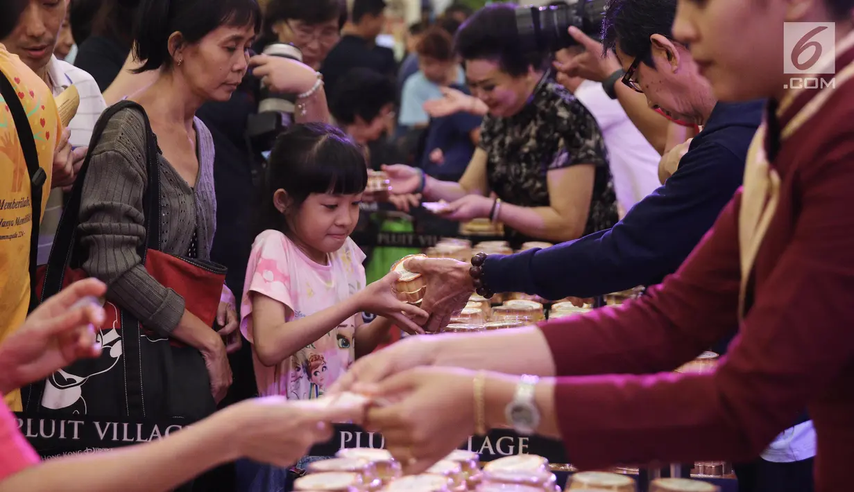 Seorang anak menerima kue bulan pada perayaan Festival Musim Gugur di Pluit Village, Jakarta, Sabtu (22/9). Festival Musim Gugur atau Festival Kue Bulan identik dengan pembagian kue bulan sebagai lambang kesejahteraan. (Liputan6.com/Herman Zakharia)