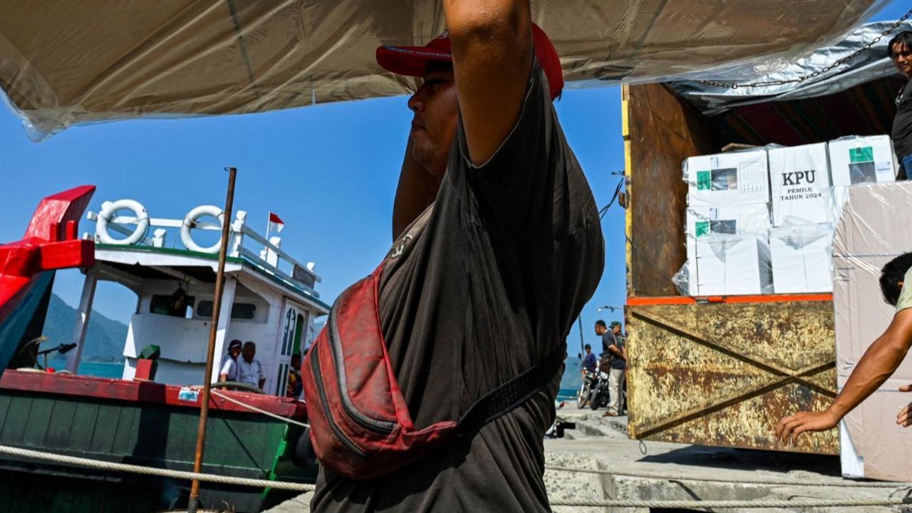 Pekerja mengangkat logistik pemilu ke atas perahu saat akan diantar menuju pulau-pulau terpencil, di Pulo Aceh, di Banda Aceh, Senin (12/2/2023). Foto: AFP / CHAIDEER MAHYUDDIN