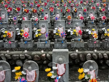 Deretan patung Jizo berdiri di Kuil Buddha Jizoji, Oganomachi, Prefektur Saitama, Jepang, Senin (13/8). Patung Jizo diyakini sebagai pelindung bagi anak-anak yang belum sempat lahir atau telah meninggal dunia. (Behrouz Mehri/AFP)
