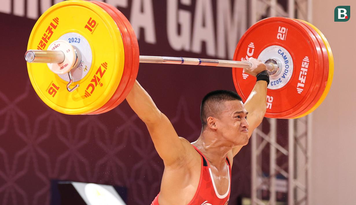 Atlet Indonesia, Rizki Juniansyah, berlaga pada cabang angkat besi 73 Kg putra SEA Games 2023 di Phnom Penh, Kamboja, Minggu (14/5/2022). Rizki Juniansyah berhasil merebut medali emas di pertandingan ini. (Bola.com/Abdul Aziz)