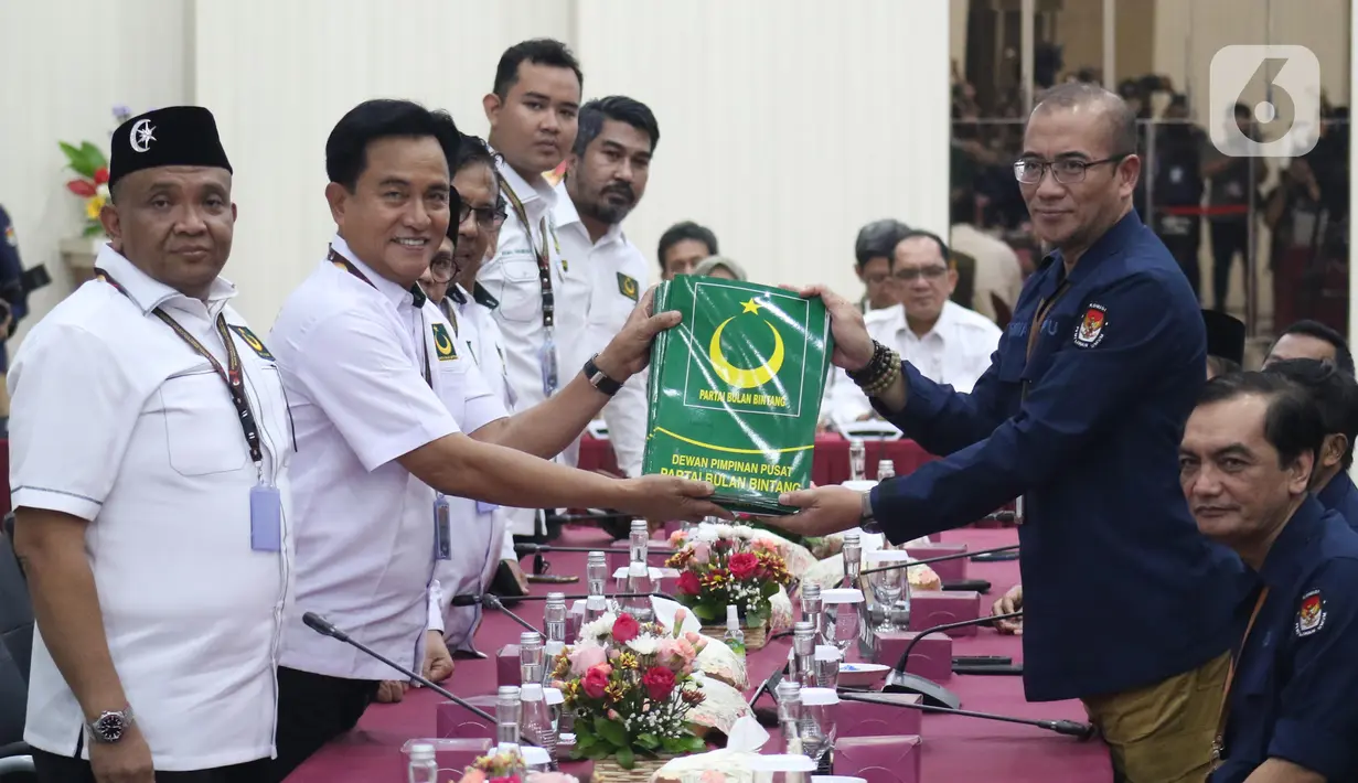 Ketua Umum Partai Bulan Bintang (PBB), Yusril Ihza Mahendra (kedua kiri berdiri) menyerahkan berkas Bakal Calon Legislatif (Bacaleg) kepada Ketua Komisi Pemilihan Umum (KPU) Republik Indonesia, Hasyim Asy'ari di Gedung KPU RI, Jakarta, Sabtu (13/5/2023). (Liputan6.com/Helmi Fithriansyah)