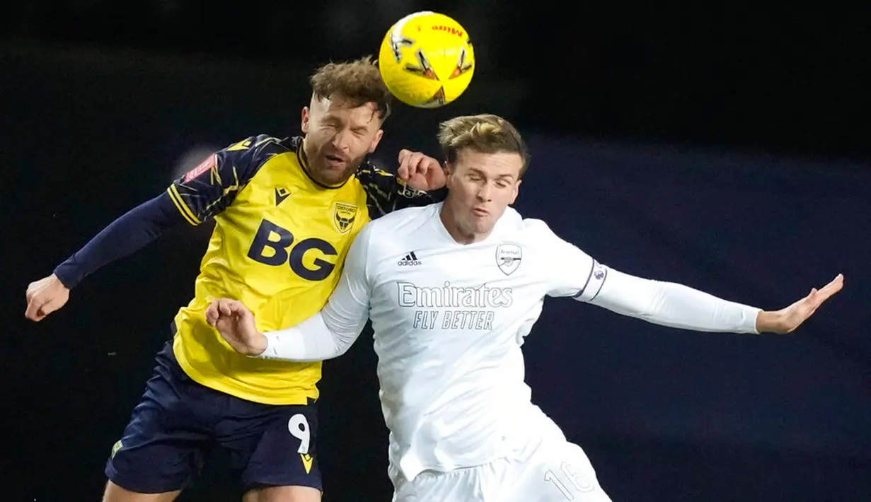 Pemain Oxford United Matty Taylor (kiri) melompat untuk merebut bola dengan pemain Arsenal Rob Holding pada pertandingan sepak bola Piala FA di Stadion Kassam, Oxford, Inggris, 9 Januari 2023. Arsenal menang 3-0. (AP Photo/Frank Augstein)