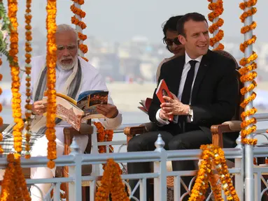 Presiden Prancis Emmanuel Macron (kanan) ditemani Perdana Menteri (PM) India Narendra Modi (kiri) menyusuri Sungai Gangga di Kota Varanasi, India, Senin (12/3). Macron mengunjungi India selama empat hari. (Ludovic MARIN/POOL/AFP)