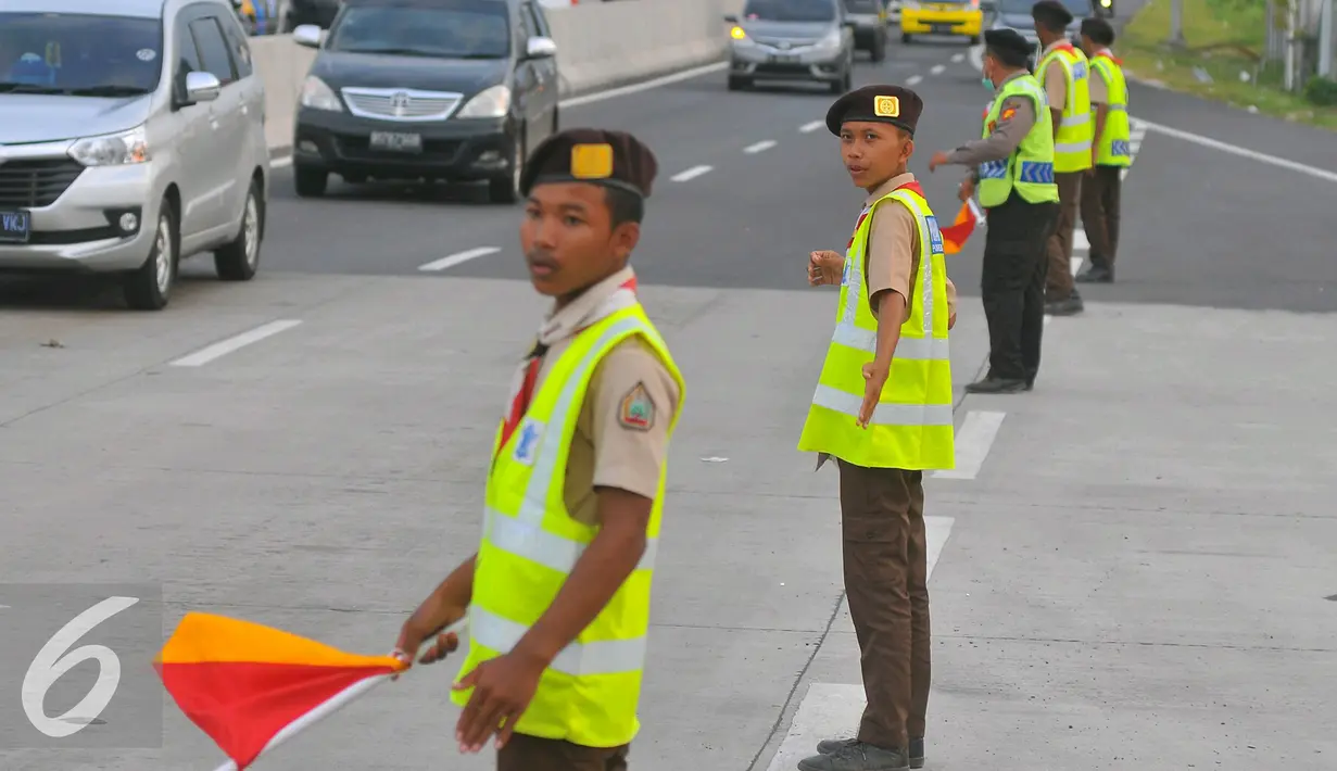 Anggota Pramuka memberi arahan kepada pengguna jalan di pertigaan pintu keluar tol Brebes, Jawa Tengah, Jumat (23/12). Selain polisi, sejumlah relawan dari anggota Pramuka ikut membantu kelancaran arus mudik Natal 2016. (Liputan6.com/Angga Yuniar)