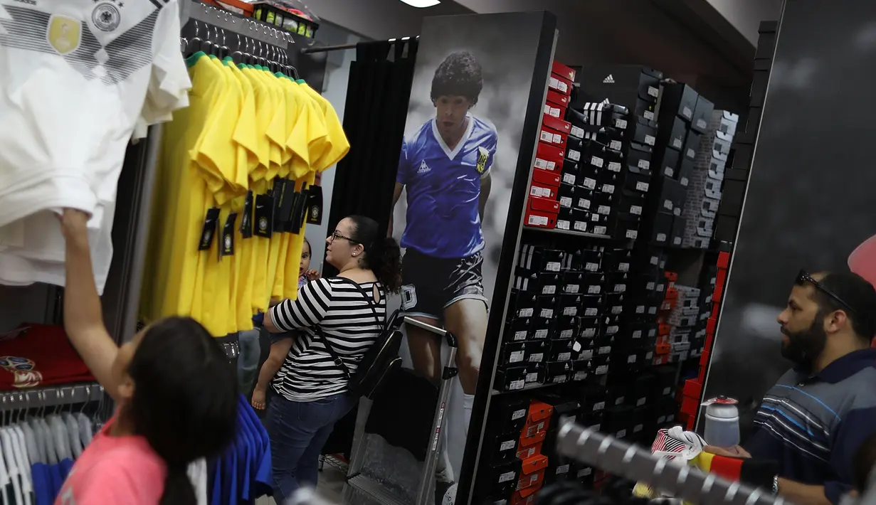 Sebuah keluarga memilih pernak-pernik timnas Jerman di toko Soccer Locker, Florida, Rabu (13/6). Suporter sudah meramaikan pusat perbelanjaan untuk mendukung timnas Jerman yang akan berlaga di Piala Dunia 2018 Rusia. (Joe Raedle/Getty Images/AFP)