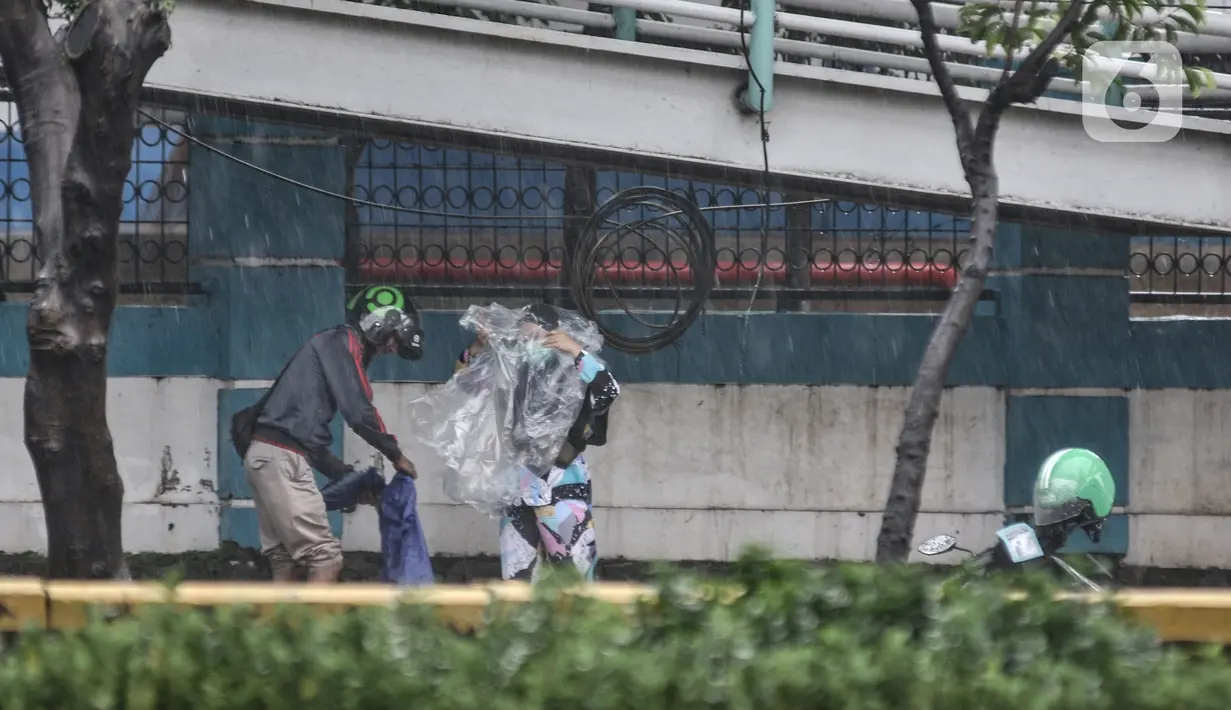 Pengendara motor mengenakan jas hujan di Jalan Pramuka, Jakarta, Kamis (18/2/2021). BMKG mengimbau pengguna jalan agar berhati-hati saat berkendara karena musim hujan disertai angin kencang diprediksi terus berlanjut hingga akhir Februari. (merdeka.com/Iqbal S Nugroho)