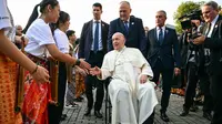 Sebelum masuk ke dalam, Paus Fransiskus berkeliling menemui sejumlah anak yang berdiri menjadi pagar betis menyambut kedatangannya. (Tiziana FABI/AFP)