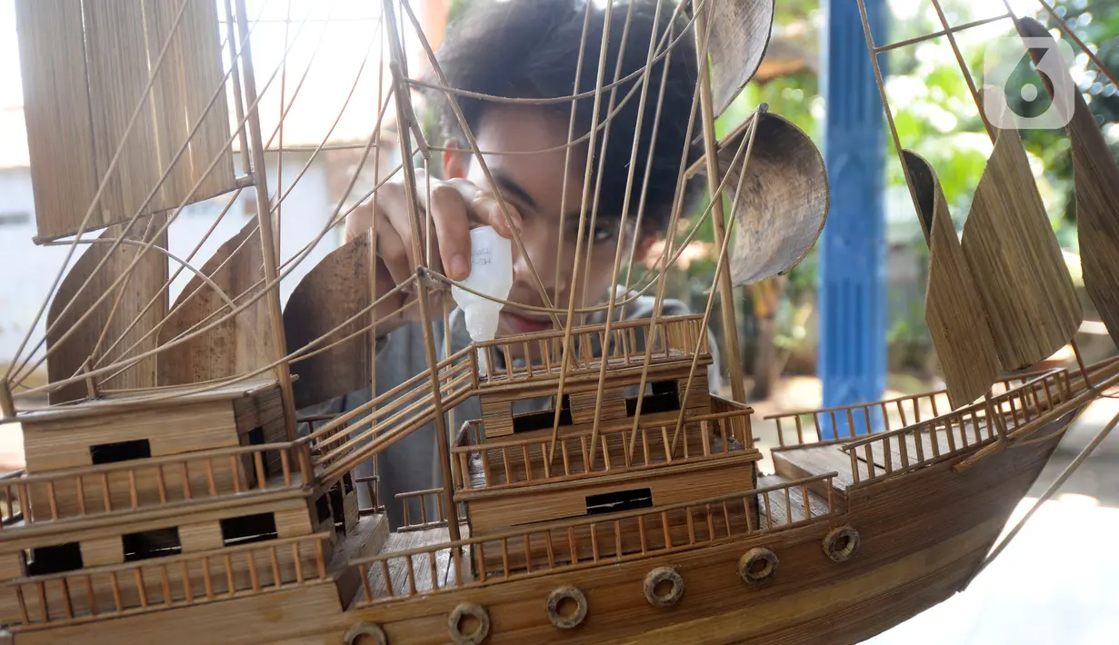 Perajin menyelesaikan pembuatan miniatur kapal pinisi yang terbuat dari limbah bambu di Pondok Benda, Pamulang, Tangerang Selatan, Senin (09/11/2020). Kerajinan berbahan bambu bekas yang dijual dengan harga berkisar Rp.50 ribu hingga Rp.250 ribu tergantung ukurannya. (merdeka.com/Dwi Narwoko)