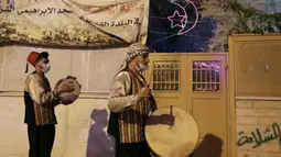 Pria Palestina yang dikenal dengan "Musaharatis" saat bertugas sebagai "penabuh drum Ramadhan" di kota tua Hebron, Tepi Barat pada 14 April 2021. Membangunkan sahur sudah menjadi tradisi yang sudah mereka lakukan selama Ramadhan. (HAZEM BADER/AFP)