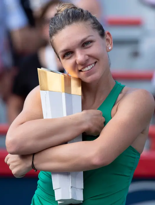 Petenis Rumania, Simona Halep memeluk trofi Kanada Terbuka 2018 setelah menaklukkan petenis AS, Sloane Stephens di Montreal, Minggu (12/8). Halep sukses menumbangkan Stephens dengan skor akhir 7-6(6), 3-6, 6-4. (Paul Chiasson/The Canadian Press via AP)