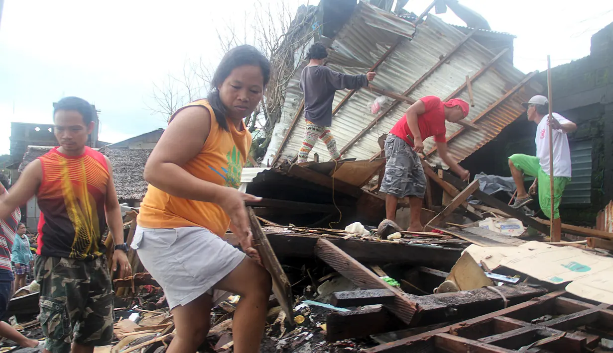 Warga merapihkan puing puing di desa Pigcale pesisir pantai yang terkena Topan Melor, di kota Legazpi, provinsi Albay, Filipina (15/12). Dasyat Topan Melor menyebabkan banjir, badai 800.000 orang dievakuasi dari Filipina tengah. (REUTERS/Rhaydz Barcia)