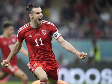 Berstatus tim debutan di Piala Dunia 2022, Wales sukses meraup satu poin dan terhindar dari kekalahan dalam laga menghadapi Amerika Serikat pada matchday pertama Grup B, Selasa (22/11/2022) dini hari WIB. Bertanding di Ahmad Bin Ali Stadium, Doha, Qatar, Gareth Bale dkk berbagi skor 1-1 dengan Tim Paman Sam. Tertinggal lebih dahulu lewat gol Timothy Weah pada babak pertama, Wales baru berhasil menyamakan skor pada menit ke-82 via eksekusi penalti Gareth Bale. (AP/Ashley Landis)