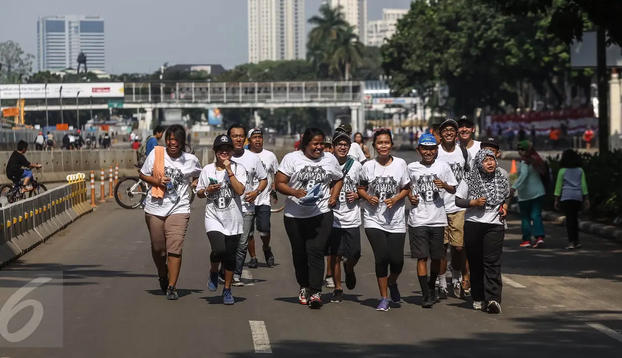 Sejumlah anak muda mengenakan kaos bertuliskan kawan8 berlari saat Car Free Day di kawasan Senayan, Jakarta, Minggu (24/7). Kegiatan ini dilaksanakan dalam rangka memperingati hari keadilan internasional. (Liputan6.com/Fery Pradolo)