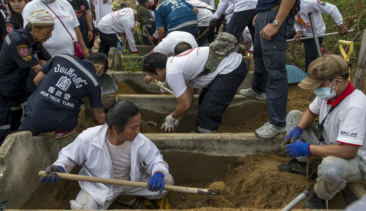 Relawan saat menggali makam tanpa identitas di pemakaman Poh Teck Tung, Thailand, Selasa (3/11/2015). Sebuah upacara kremasi massal Buddha akan diadakan pada bulan November untuk mendoakan para jenazah ini. (REUTERS/Athit Perawongmetha)