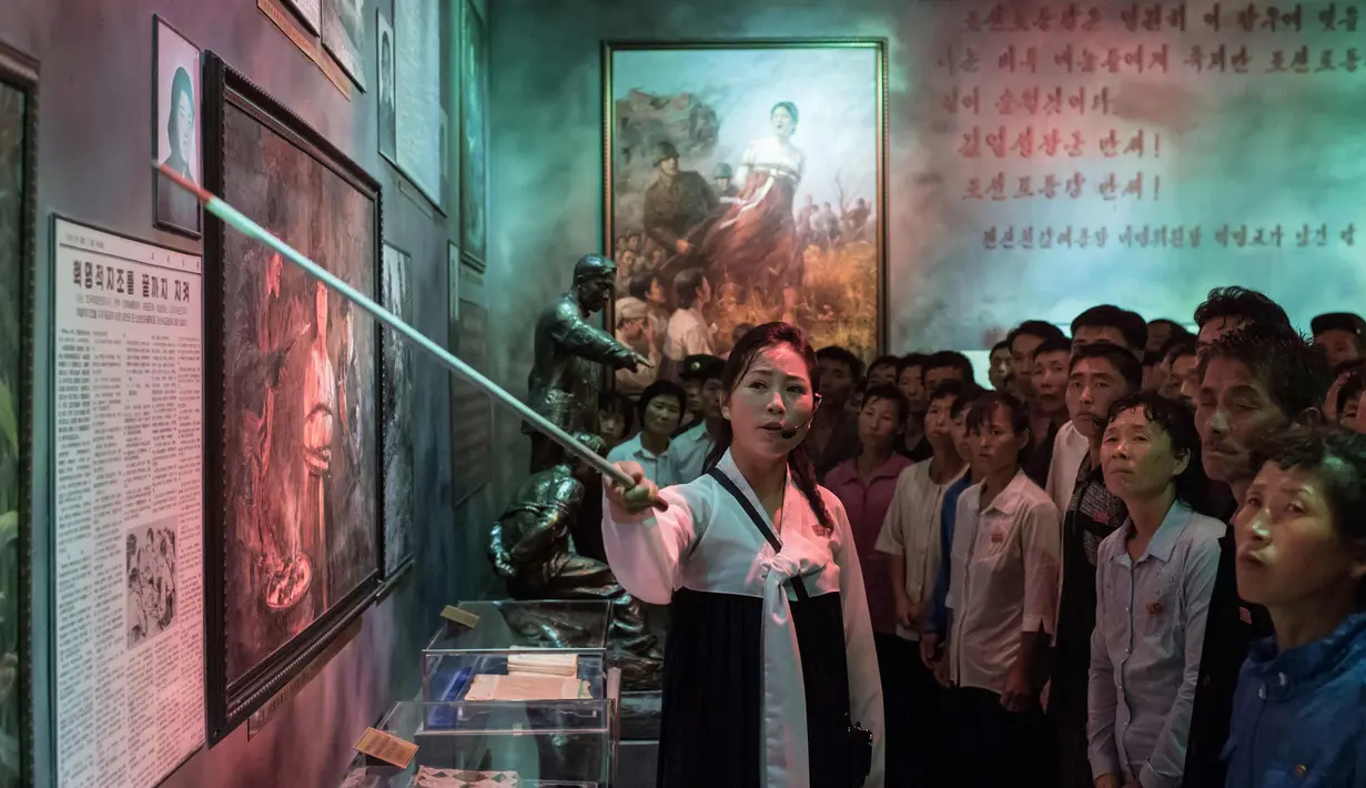 Pemandu menunjukkan lukisan di Sinchon Museum of American War Atrocities di Pyongyang 24 Juli 2017. Museum ini menampilkan kejadian pembantaian yang diduga dilakukan oleh angkatan bersenjata AS dan Korsel pada Perang Korea 1950-1953. (AFP Photo/Ed Jones)