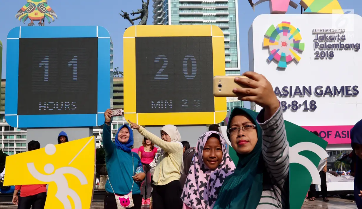 Warga swafoto dengan latar layar Countdown Asian Games 2018 saat Car Free Day di Bundaran HI, Jakarta, Minggu, (10/09). Asian Games akan berlangsung pada 18 Agustus hingga 2 September 2018. (Liputan6.com/Fery Pradolo)