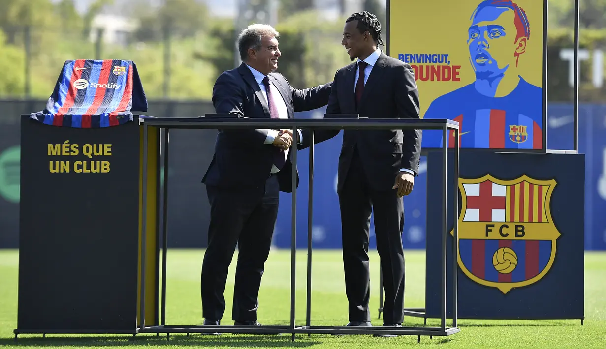 <p>Bek baru Barcelona dari Prancis Jules Kounde (kanan) berjabat tangan dengan Presiden Barcelona Joan Laporta saat upacara presentasi di tempat latihan Joan Gamper di Sant Joan Despi, Barcelona (1/8/2022). Barcelona merogoh kocek cukup dalam untuk mendatangkan Kounde. Dari Sevillia, Kounde ditebus dengan harga 50 juta Euro atau setara Rp762,38 miliar. (AFP/Pau Barrena)</p>