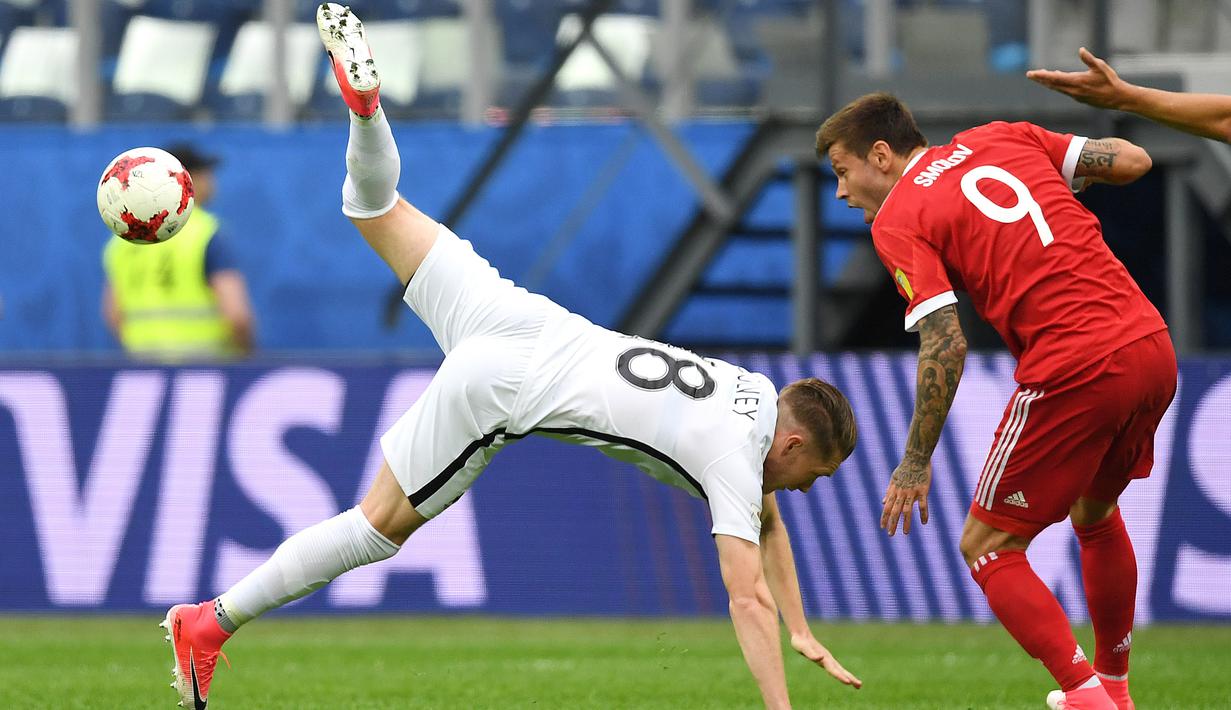 Bek Selandia Baru, Kip Colvey (kiri) terjatuh saat berduel dengan pemain Rusia, Fedor Smolov pada Piala Konfederasi 2017 grup A di Krestovsky Stadium, Saint-Petersburg, (17/6/2017).  (AFP/Kirill Kudryavtsev)