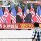 Pejalan kaki melihat layar yang menampilkan pertemuan antara pemimpin Korea Utara Kim Jong-un dan Presiden AS Donald Trump di Tokyo, Selasa (12/6). Untuk pertama kalinya dalam sejarah, Donald Trump dan Kim Jong-un bertemu. (AFP PHOTO/Martin BUREAU)