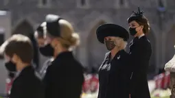 Kate Middletone, Duchess of Cambridge (kanan) berdiri menjelang pemakaman Pangeran Philip di kastil Windsor, Inggris (17/4/2021). Kate Middletone, Duchess of Cambridge tampil memesona dengan busana dan masker hitam. (Victoria Jones/Pool via AP)