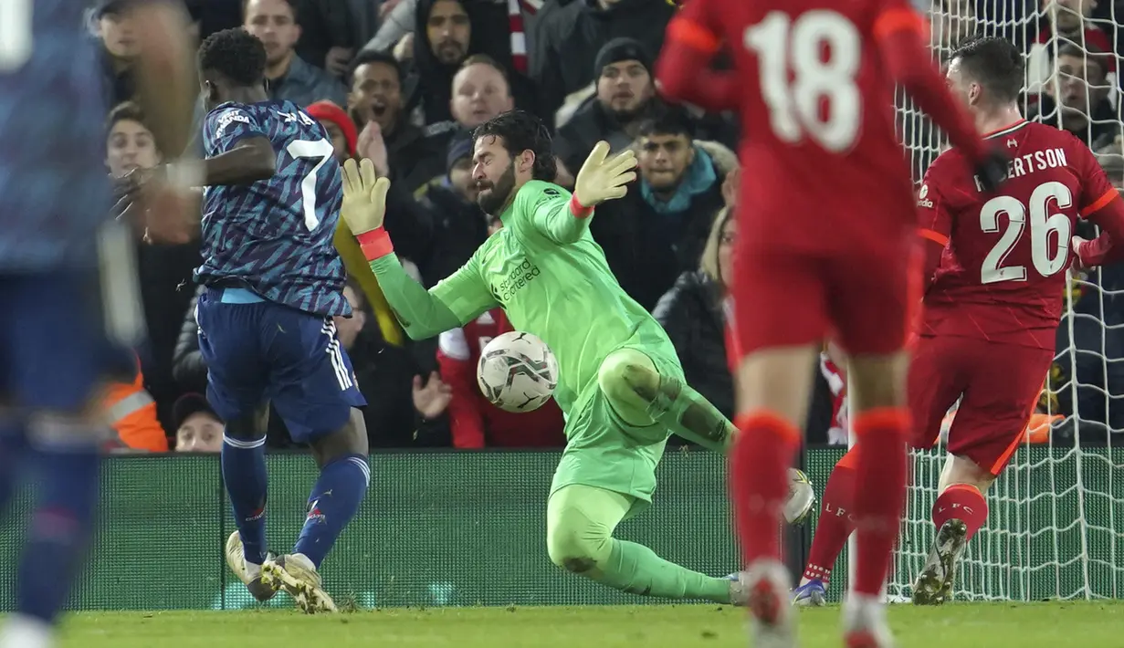 Gelandang Arsenal Bukayo Saka gagal mencetak gol di depan kiper Liverpool Alisson pada leg pertama semifinal Piala Liga Inggris di Stadion Anfield, Jumat (14/1/2022) dinihari WIB. Arsenal dipkasa bermain imbang tanpa gol oleh Liverpool. (AP Photo/Jon Super)