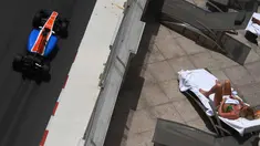 Pebalap Manor Racing, Pascal Wehrlein, melintas di dekat seorang turis yang sedang berjemur sambil menyaksikan latihan bebas F1 GP Monako di sirkuit jalan raya Monako. (AFP/Pascal Guyot)