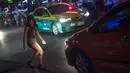 Foto pada 11 Oktober 2018 menunjukkan seorang wanita menyebrang jalan di Nana Red Light Distrik, Bangkok, Thailand. Nana Red Light District memang dikenal sebagai kawasan hiburan malam terbesar di Bangkok. (Romeo GACAD / AFP)
