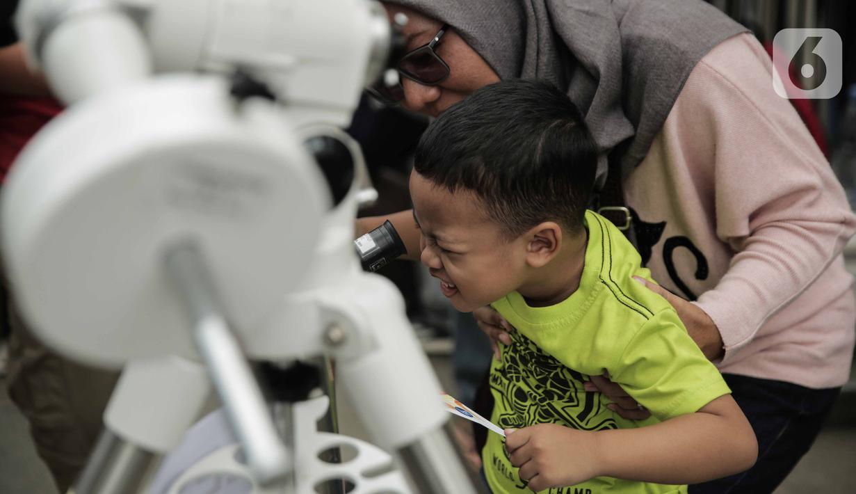 Pengunjung mengamati gerhana matahari cincin menggunakan teleskop di Planetarium Taman Ismail Marzuki, Jakarta, Kamis (26/12/2019). Planetarium menyediakan sekitar 10 teleskop dan kacamata khusus agar pengunjung bisa menyaksikan gerhana matahari cincin dengan aman. (Liputan6.com/Faizal Fanani)