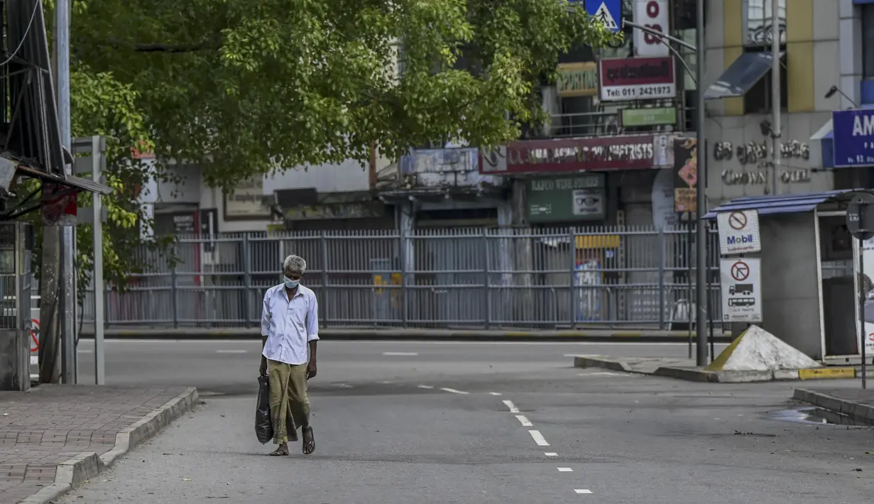 Seorang pria berjalan melalui jalan yang sepi setelah pemerintah memberlakukan pembatasan perjalanan dan lockdown akhir pekan di Kolombo, Sri Lanka, Sabtu (22/5/2021). Sri Lanka pada Jumat, 21 Mei mencatat 3.547 kasus harian corona Covid-19. (Ishara S. KODIKARA/AFP)