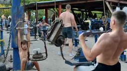 Aktivitas sejumlah orang melakukan latihan fitnes di sebuah gym outdoor di Ibu Kota Ukraina, Kiev, 18 Agustus 2017. Tanpa dipungut biaya, taman Kachalka menjadi tempat olahraga favorit pria di Kiev. (GENYA SAVILOV/AFP)