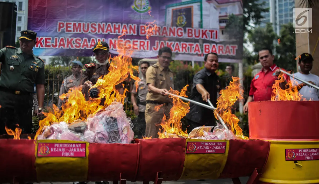 Petugas Kejaksaan bersama pihak kepolisian dan pengadilan membakar barang bukti tindak pidana umum di lapangan Kejaksaan Negeri Jakarta Barat, Selasa (11/12). (Liputan6.com/Faizal Fanani)
