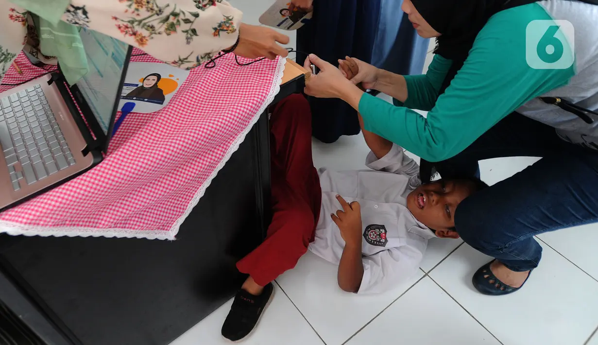 Murid SLB melakukan scaning jari saat tes STIFIn di Sekolah Luar Biasa A Pembina Tingkat Nasional, Lebak Bulus, Jakarta, Selasa (17/12/2019). Tes tesebut dilakukan melalui menscan  ksepuluh ujung jari dengan mengambil waktu tidak lebih dari satu menit. (merdeka.com/Arie Basuki)