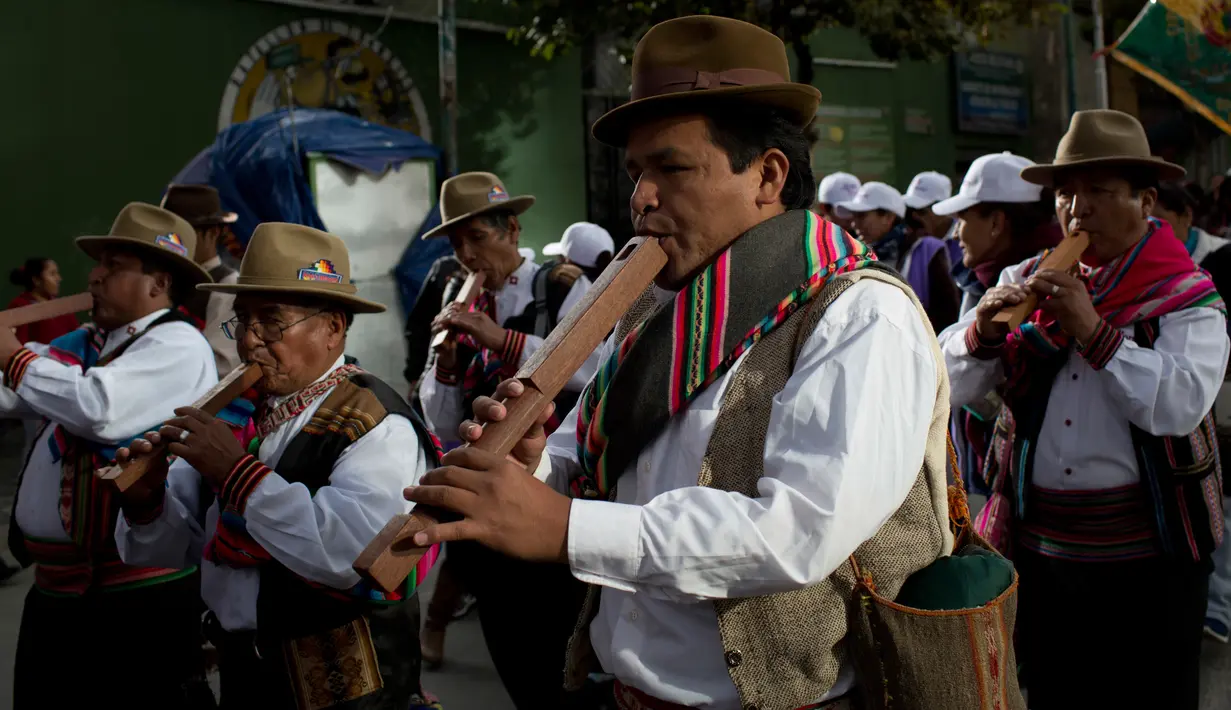 Sejumlah pemain musik pria meniupkan seruling saat prosesi arak-arakan patung dewa Ekeko di La Paz, Bolivia (23/1). Porsesi ini merupakan bagian dari acara pameran miniatur Alasita. (AP Photo / Juan Karita)