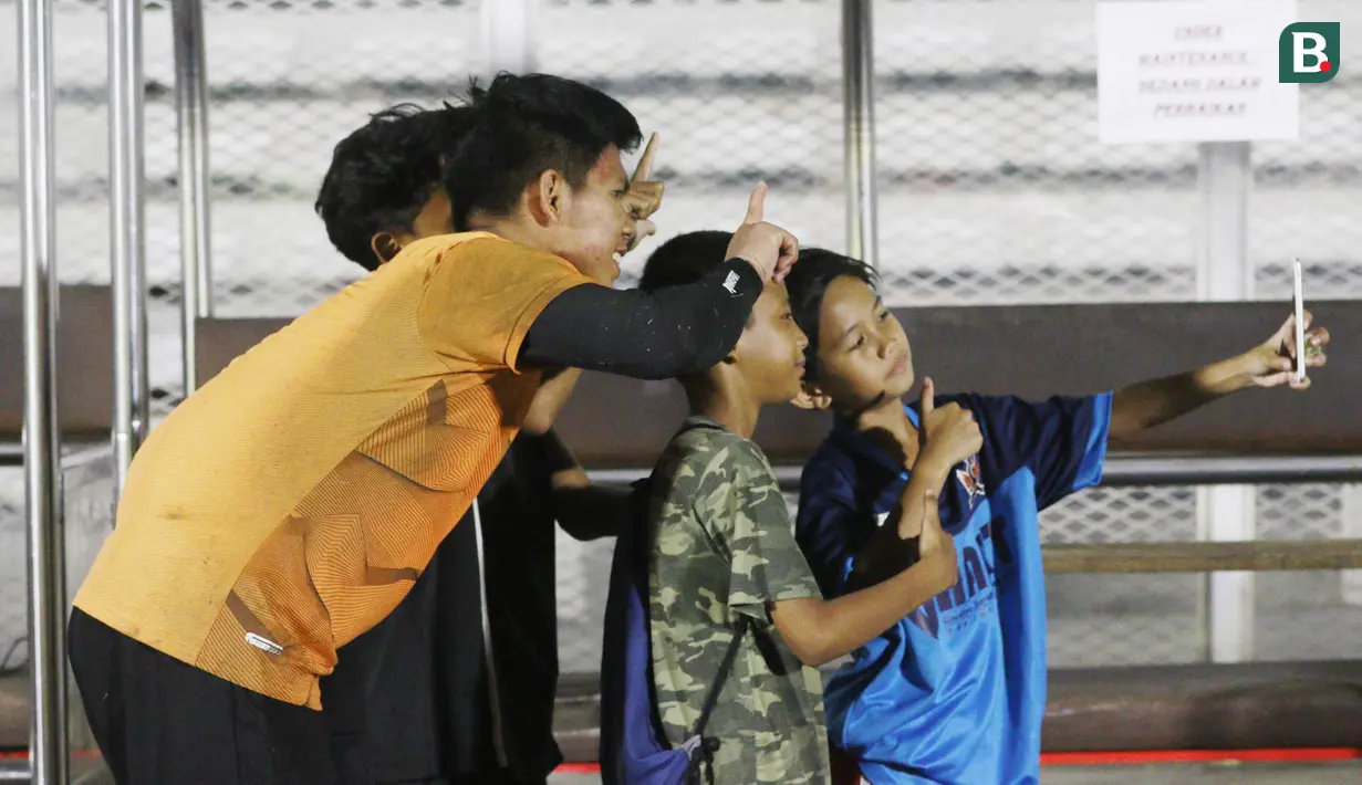 Fans cilik foto bersama dengan kiper Timnas Indonesia U-19, Cahya Supriadi, usai melakukan latihan jelang Piala AFF U-19 2022 di Stadion Madya, Jakarta, Selasa (21/6/2022). (Bola.com/M Iqbal Ichsan)