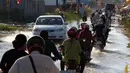 Penduduk desa mengendarai sepeda motor mereka di jalan banjir di desa Trapang Anchanh, di luar Phnom Penh, Kamboja, (27/10). (AP Photo/Heng Sinith)