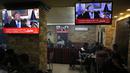 Warga Palestina berada di kafe di kota Ramallah di Tepi Barat saat sebuah siaran televisi menayangkan pidato Presiden AS, Donald Trump mengumumkan AS mengakui Yerusalem sebagai ibu kota Israel (6/12). (AFP Photo/Abbas Momani)