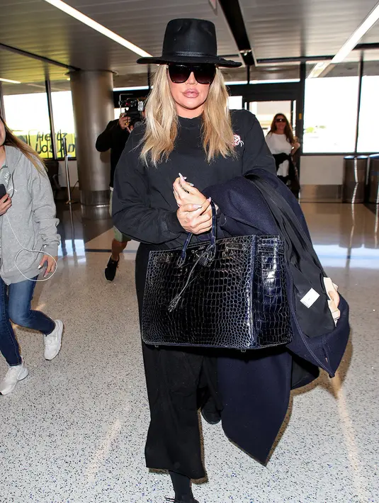 Khloe Kardashan tampul dengan pakaian serba hitam di LAX International Airport. (REX/SHUTTERSTOCK/HollywoodLife)