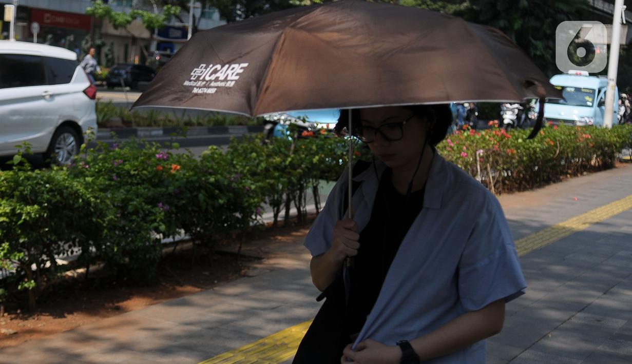 Pejalan kaki mengenakan payung untuk menghindari panas matahari di kawasan Kuningan, Jakarta, Selasa (26/9/2023). (merdeka.com/Imam Buhori)