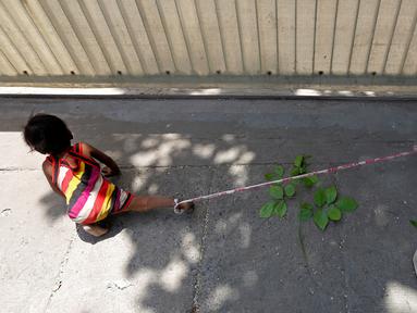 Kaki Shivani (15 bulan) terikat pada batu di bangunan di Ahmedabad, India, 20 April 2016. Dengan bertelanjang kaki, bayi itu menghabiskan 9 jam/hari di bawah suhu udara mencapai 40 derajat Celsius terikat pada tali sepanjang 1,4 meter. (REUTERS/Amit Dave)