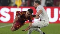 Pemain AS Roma, Paulo Dybala, terjatuh saat berusaha melewati pemain AC Milan, Ismael Bennacer, pada leg kedua perempat final Liga Europa di Stadion Olimpico, Roma, Jumat (19/4/2024). (AP Photo/Andrew Medichini)